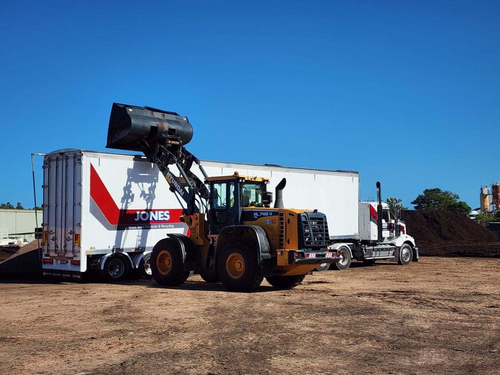 Machinery loading compost into a truck